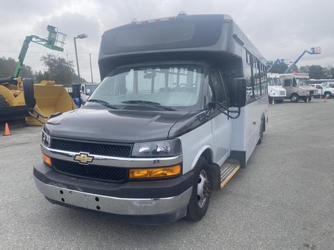 A 2017 Chevrolet Express bus with a black and white exterior featuring a large front windshield and yellow accents on the step area