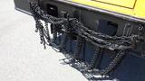 A series of black chains hanging from the rear of a 2014 International 3000 bus