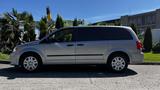 A silver 2016 Dodge Grand Caravan parked on the street with visible side profile and tinted windows