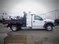 A white 2008 Ford F-550 flatbed truck with a utility body and rear storage compartments