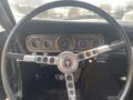 Close-up of the steering wheel and dashboard of a 1966 Ford Mustang showing vintage gauges and chrome accents