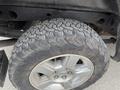 A close-up of a rugged tire on a 2013 Chevrolet Silverado Hybrid featuring a distinct tread pattern and a metallic wheel with a silver finish