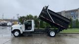 A 2021 International CV515 dump truck with its bed raised, showcasing its chassis and cabin, positioned at an angle to display the truck's features