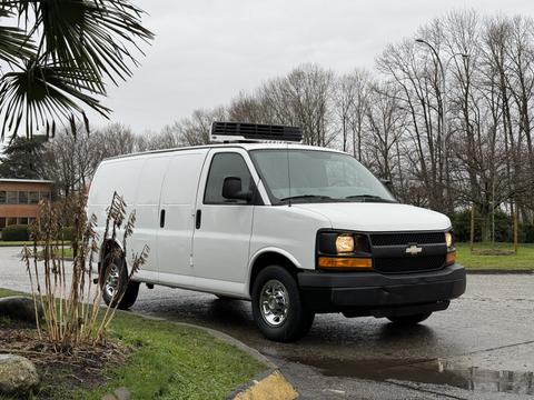 A white 2009 Chevrolet Express van with a black grille and no side windows parked on a road