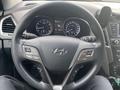 Steering wheel of a 2017 Hyundai Santa Fe featuring controls for audio and cruise settings along with dashboard displays in the background