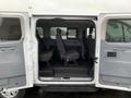 Image of the interior of a 2017 Ford Transit showcasing rows of seating with a gray fabric finish and accessible doors on both sides