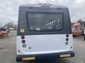 A 2018 Chevrolet Express bus viewed from the rear with a white body and black trim featuring taillights and warning signs on the back