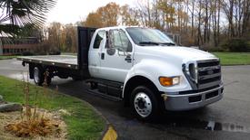 A white 2008 Ford F-650 flatbed truck with a large cargo bed and dual rear wheels parked at an angle