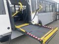 A 2017 Chevrolet Express with a deployed mobile wheelchair ramp featuring yellow handles and a textured metal surface