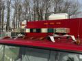 A red 1994 Freightliner FL80 with several lightbars and amber lights mounted on top of the cab