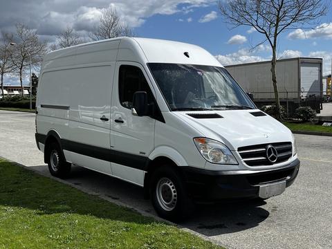 A 2012 Mercedes-Benz Sprinter van in white with a black stripe along the lower side and a large cargo area in the back