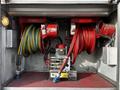 A compartment featuring two large hose reels one with yellow hose and one with red hose alongside a pump and various connectors