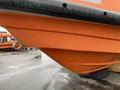 A close-up view of the bow of a 2008 Fassmer 20 Foot Fast Rescue boat featuring an orange hull with a smooth, curved design and a black rubber fender along the top edge