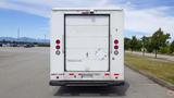 A white 2011 Ford Econoline cargo van viewed from the rear with a closed door and red taillights