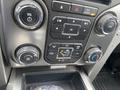 A close-up view of the control panel of a 2014 Ford F-150 featuring climate control knobs audio buttons and a digital display