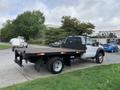 A white 2012 Ford F-550 flatbed truck with a black platform and mesh guard on the back