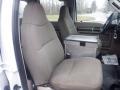 Two beige cloth seats in the cabin of a 2009 Ford F-450 SD with a metal storage box between them