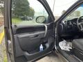 A 2013 Chevrolet Silverado Hybrid with an open door showcasing the interior features and a water bottle in the door pocket