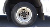 A close-up view of a white tire and wheel from a 2011 Ford Econoline showing tire tread and metal wheel bolts