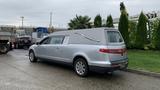 A silver 2013 Lincoln MKT hearse with a smooth body and elongated design featuring a casket compartment and a chrome decorative feature on the side