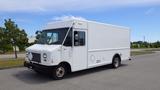 A white 2011 Ford Econoline cargo van with a flat front design and sliding side door parked on a road