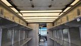 Interior of a 2006 Ford Econoline with metal shelves on either side and an open ceiling revealing a tarp