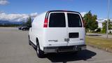 A white 2015 GMC Savana van parked with its rear doors closed and visible brand markings on the back