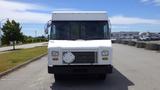 A white 2011 Ford Econoline van with a flat front and a blank license plate area is parked on a paved lot