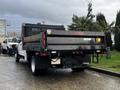 A 2021 Ford F-550 flatbed truck with a black dump bed and red accents parked in a lot