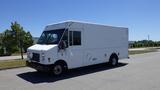 A white 2006 Ford Econoline delivery truck with a boxy shape large windows and front grille parked on a paved area