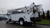 A 2005 International 4300 bucket truck with a raised aerial lift and a large utility body for carrying equipment and tools