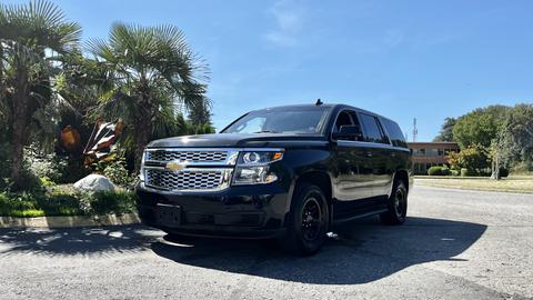 A black 2018 Chevrolet Tahoe parked on a street with a visible front view showcasing its chrome grille and sleek body design