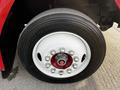 Close-up of a wheel and tire from a 1994 Freightliner FL80 featuring a white rim with shiny lug nuts and a black tire with visible size markings