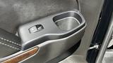 Interior door handle and cup holder of a 2018 Chevrolet Tahoe showcasing a black textured surface and wood grain accent