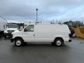 A white 2013 Ford Econoline van with a smooth exterior and roof racks parked in a lot