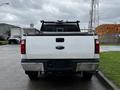 White 2011 Ford F-250 SD viewed from the rear with a black grille and a metal bed cover