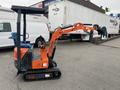 A compact orange and black excavator with a tracked base and a small operator cabin featuring a protective roof and a digging arm with a bucket.