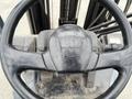 Close-up of a 2011 Toyota forklift steering wheel showing the Toyota logo and various controls on the dashboard