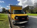 A yellow 2017 GMC Savana with a box truck design parked along a curb with a gray front bumper and distinctive GMC grille