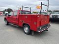 A red 2011 Ford F-250 SD with a utility bed and a safety flag attached to a metal frame on the truck's rear