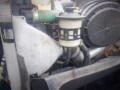 Close-up of the engine components of a 2008 International 7400 showing a metallic cover a green hose and a cylindrical filter with black and white features