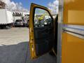 A yellow 2017 GMC Savana van with the driver's side door open showing the interior panel and controls