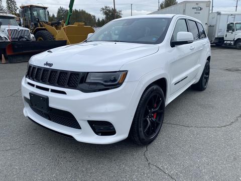 A white 2018 Jeep Grand Cherokee with a sleek design featuring a black grille and sporty black wheels