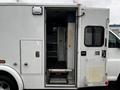 A 2016 Chevrolet Express van with an open side door showing a set of steps leading inside and shelves visible in the interior