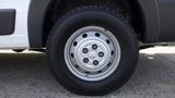 A close-up of a silver wheel on a black tire of a 2017 RAM Promaster showing five lug nut openings in the rim